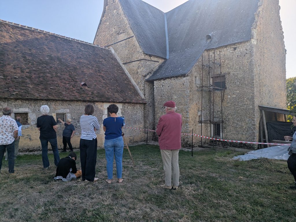 Un petit groupe pendant la visite, attentif à une explication ou réuni autour d’un support visuel et du propriétaire lors de sa visite commentée